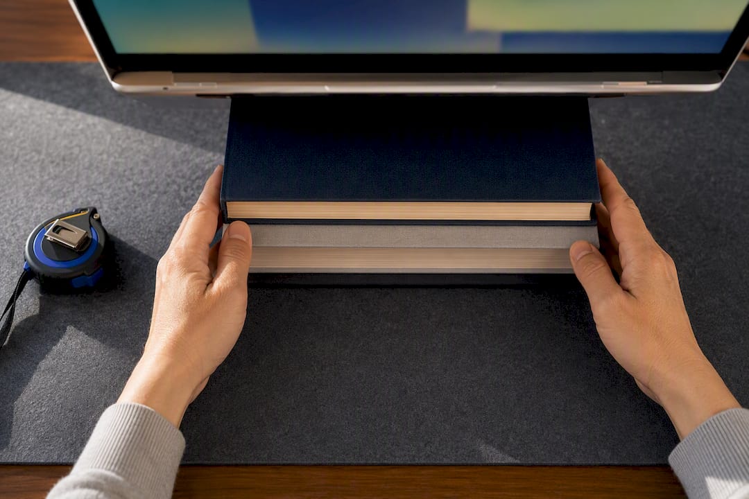 Books raising laptop to eye level